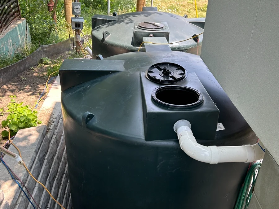 Eco Water Solutions dual rainwater harvesting storage tanks installed with filtration and plumbing connections at a Texas home